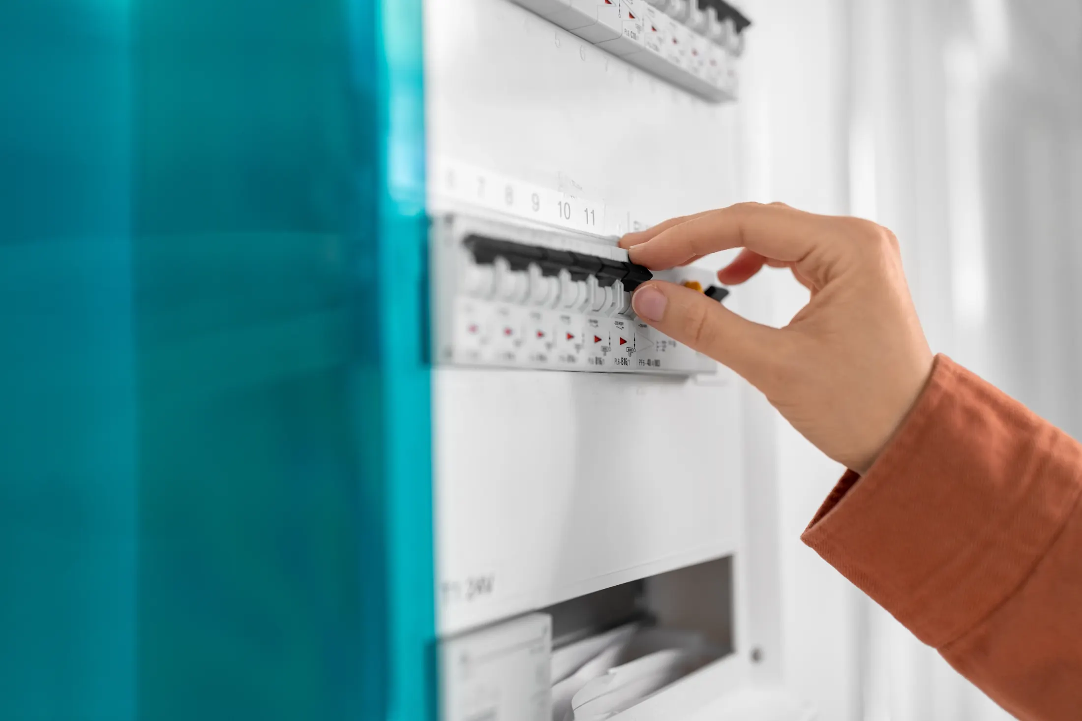 Close-up of a hand switching a breaker inside a home electrical panel