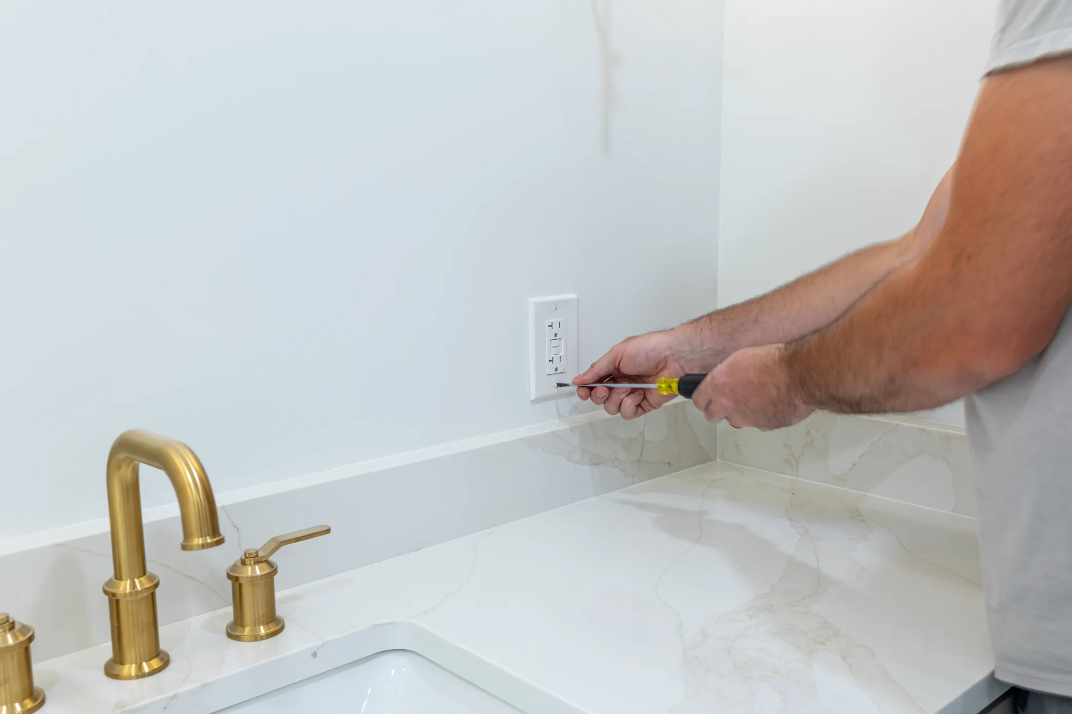 Electrician installing a GFCI outlet on a bathroom wall