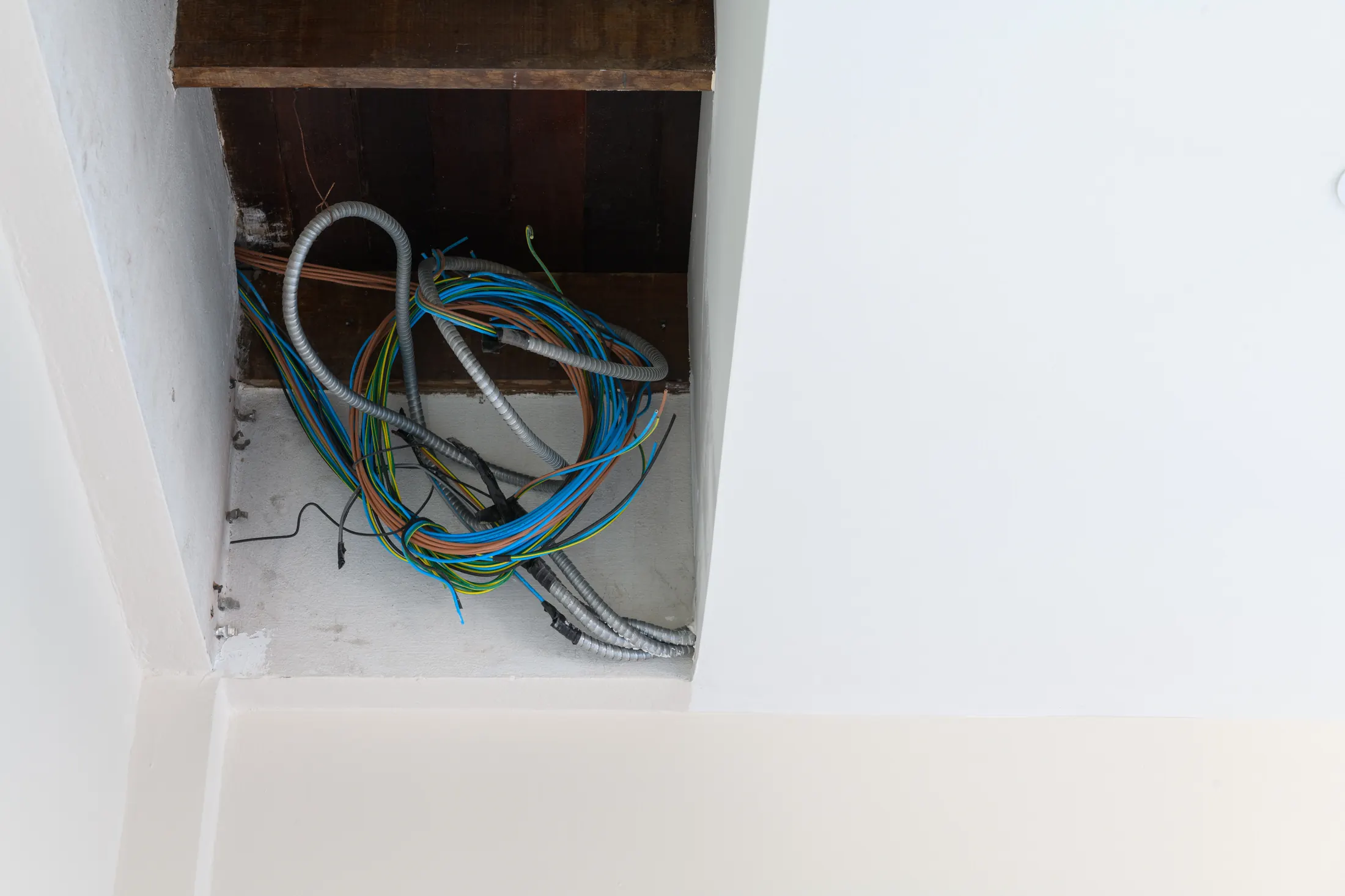Bundle of electrical wiring exposed inside a ceiling during a home rewiring project